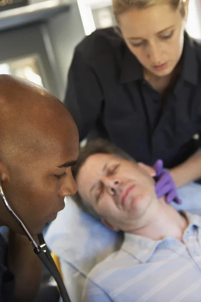 Paramedic using stethoscope on patient in ambulance — Stock Photo, Image