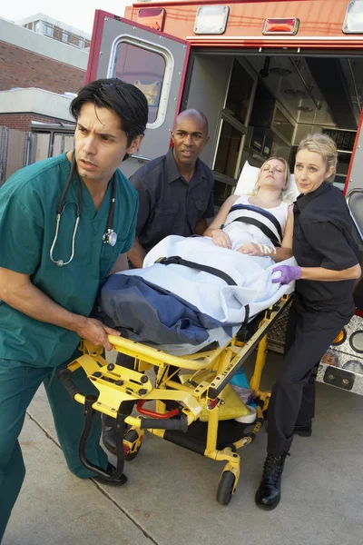 Paramédicos e médico descarregando paciente de ambulância — Fotografia de Stock