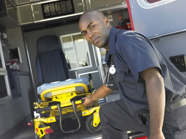 Paramédico removendo maca vazia da ambulância — Fotografia de Stock
