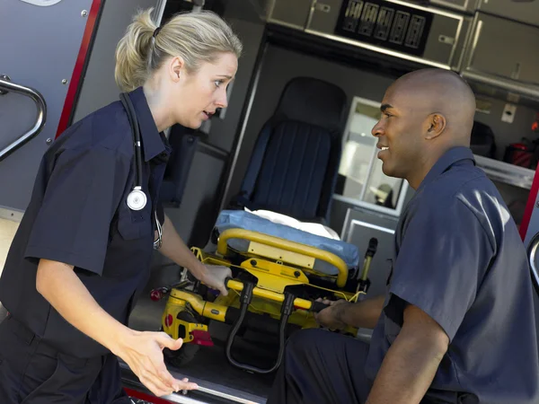 Twee paramedici vrolijk verwijderen lege gurney van ambulance — Stockfoto