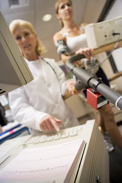 监测心率的跑步机上的病人的医生 — 图库照片