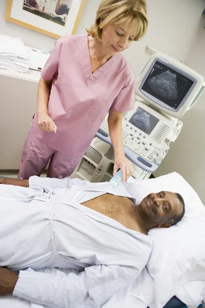 Enfermeira a verificar o paciente deitado na cama do hospital — Fotografia de Stock