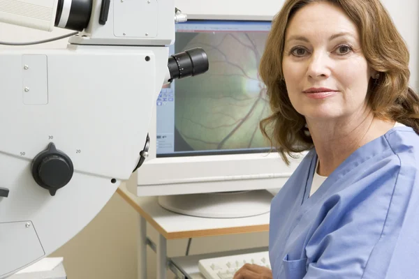 Retrato de uma enfermeira ao lado de uma máquina de exame ocular — Fotografia de Stock