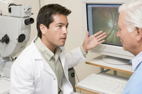 Médico explicando los resultados del examen ocular al paciente — Foto de Stock