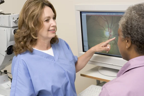 Krankenschwester erklärt Patienten Ergebnisse von Augenuntersuchungen — Stockfoto