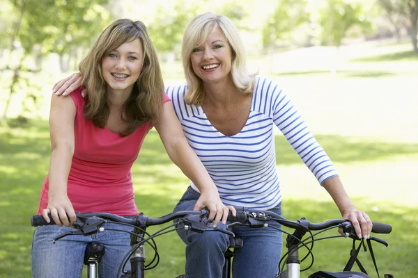Mãe e filha de bicicleta através de um parque — Fotografia de Stock