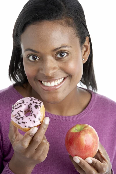 Frau hat die Wahl zwischen Apfel und Donut — Stockfoto