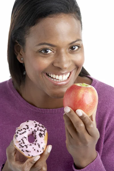 苹果和甜甜圈之间进行选择的女人 — 图库照片