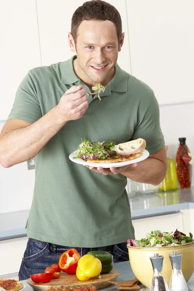 Людина їсть їжу на кухні — стокове фото