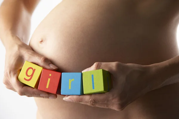 孕妇拿块拼写"女孩" — 图库照片