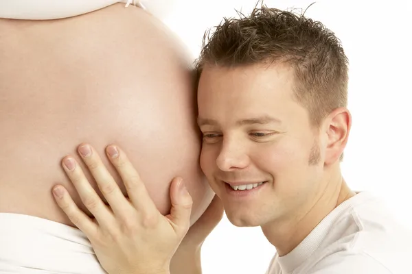 男人听着孕妇的肚子 — 图库照片
