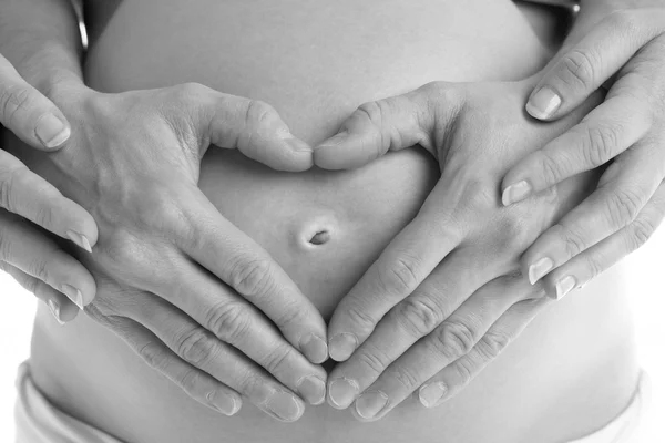 Detalle de la mujer embarazada que forma la forma del corazón con las manos — Foto de Stock