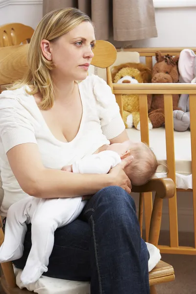 Mãe preocupada amamentando bebê no berçário — Fotografia de Stock