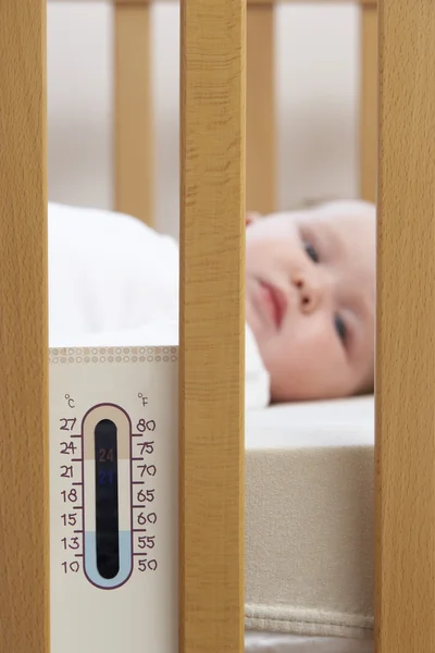 生まれたばかりの赤ちゃん温度計とベビーベッドで — ストック写真
