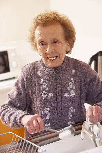 シンクで食器洗いを年配の女性 — ストック写真