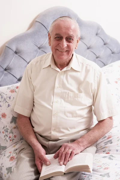 Senior man lezen boek op bed — Stockfoto