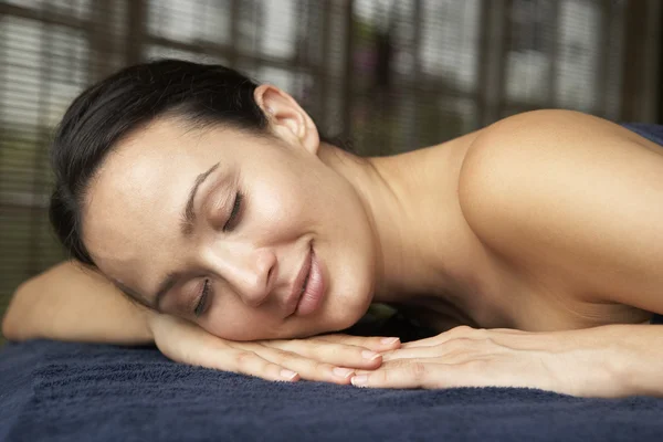 Jovem mulher relaxante na mesa de massagem — Fotografia de Stock