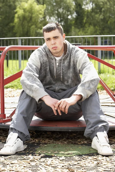 Junger Mann Sitzt Auf Spielplatz — Stockfoto