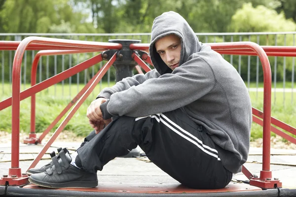Junger Mann Sitzt Auf Spielplatz — Stockfoto