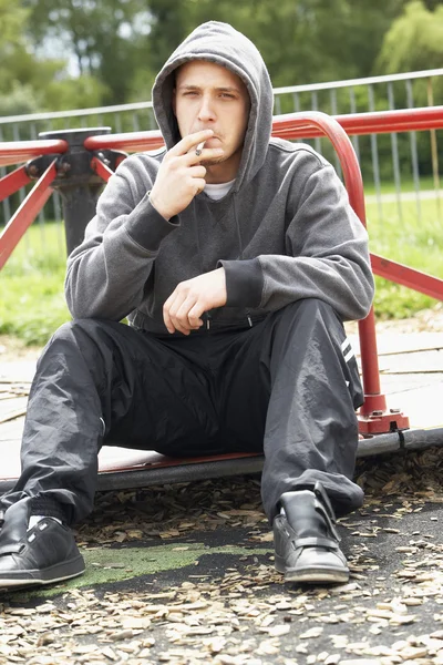 Νεαρός Άνδρας Που Κάθονται Στην Παιδική Χαρά Κάπνισμα Άρθρωση — Φωτογραφία Αρχείου