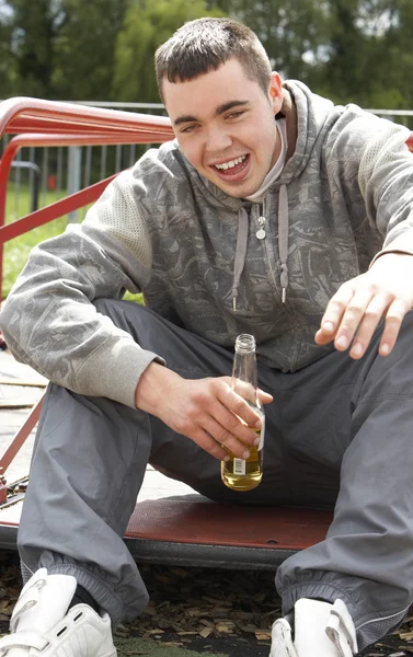 遊び場のビールを飲みに座っている若い男 — ストック写真