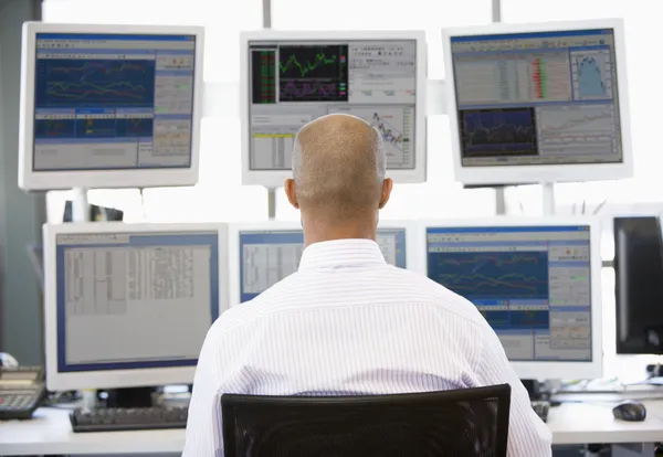 Aktienhändler blickt auf mehrere Monitore — Stockfoto