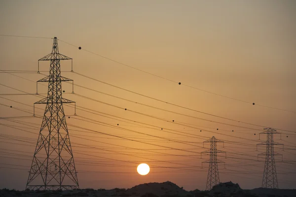 Kraftledningsstolparna silhuett i solnedgången — Stockfoto