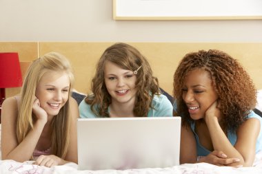 Group Of Three Teenage Girls Using Laptop In Bedroom clipart