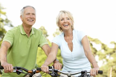 Mature couple riding bikes clipart