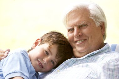 Grandfather Hugging Grandson In Park clipart