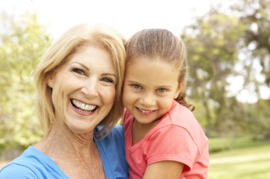 Grandaughter Hugging Grandmother In Park clipart