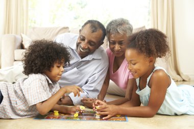 Grandparents Playing Board Game At Home With Grandchildren clipart