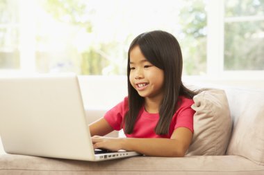 Young Girl Using Laptop At Home clipart