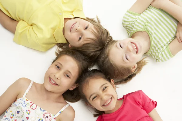 Cirkel van vier jonge vrienden liggen glimlachen — Stockfoto