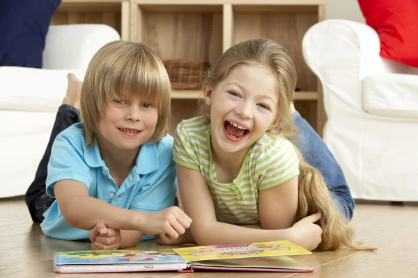 Двое маленьких детей читают книгу дома — стоковое фото
