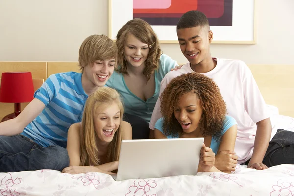 Skupina pěti dospívající pomocí notebooku v ložnici — Stock fotografie