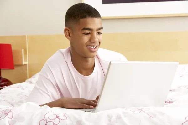 Nastoletni chłopiec korzysta z laptopa w sypialni — Zdjęcie stockowe