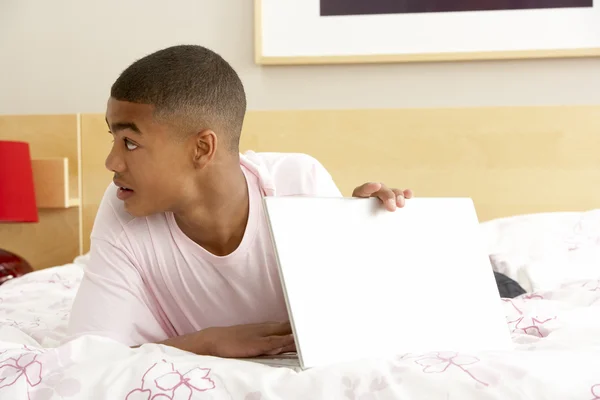 Coupable adolescent garçon à l'aide d'ordinateur portable dans la chambre — Photo