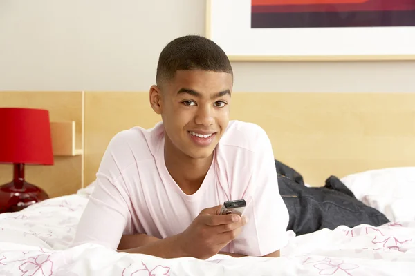 Menino adolescente no quarto com telefone móvel — Fotografia de Stock