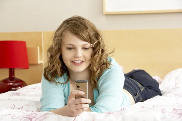 Chica adolescente en el dormitorio con teléfono móvil —  Fotos de Stock