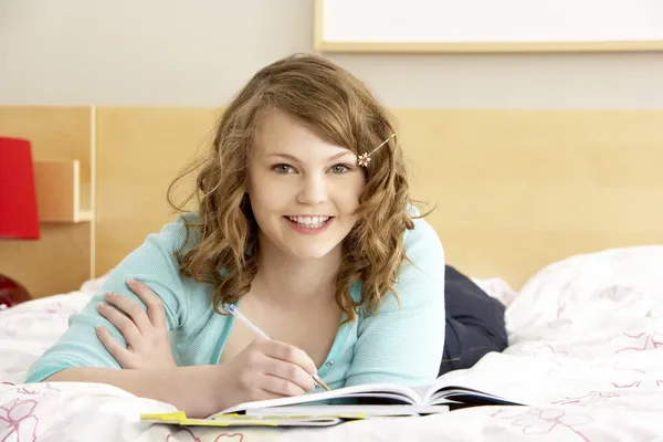 Adolescente chica escribiendo en diario en el dormitorio — Foto de Stock