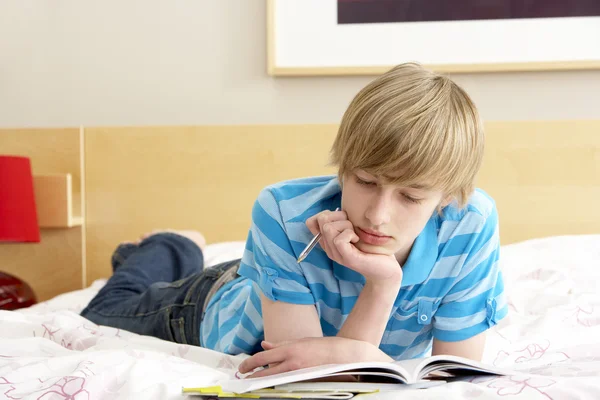 Nastoletni chłopak pisze w pamiętniku w sypialni — Zdjęcie stockowe
