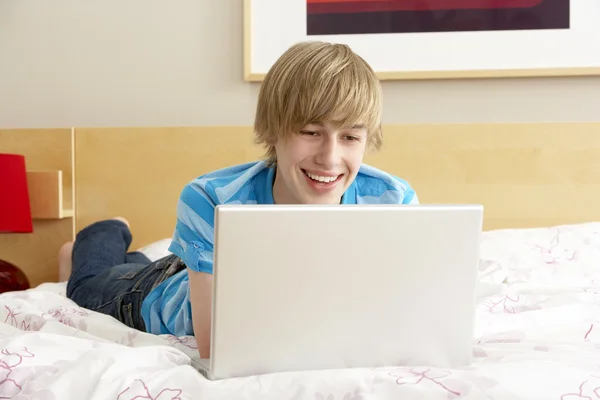十几岁的男孩在卧室使用便携式计算机 — 图库照片