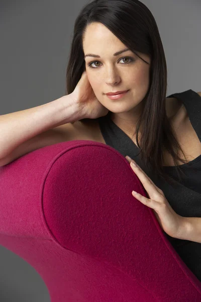 女性ピンク寝椅子にリラックスのスタジオ ポートレート — ストック写真
