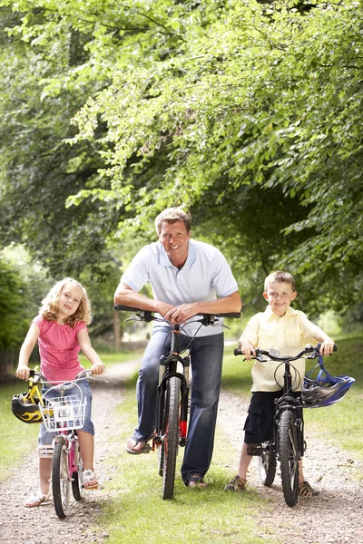 Pai e crianças andando de bicicleta no campo — Fotografia de Stock