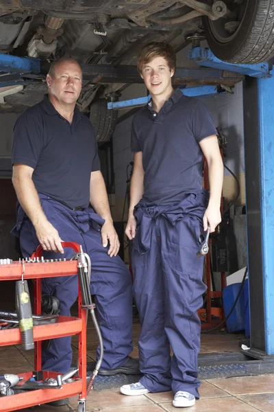 Mechanic and apprentice working on car — Stock Photo, Image