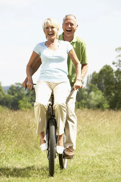 Äldre par ridning cykel på landsbygden — Stockfoto