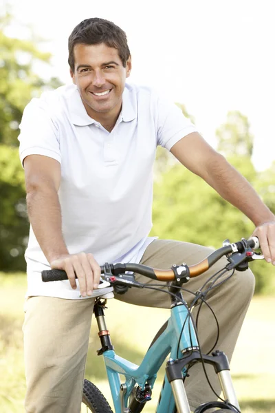 Giovane uomo in bicicletta in campagna — Foto Stock