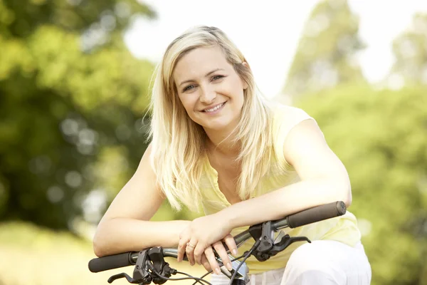 Jonge vrouw rijden fiets in platteland — Stockfoto