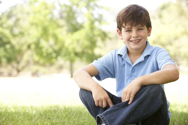 Retrato de menino jovem sentado no parque — Fotografia de Stock